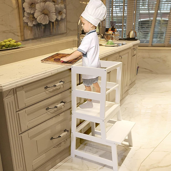 A boy using a safety stool to help in the kitchen. 