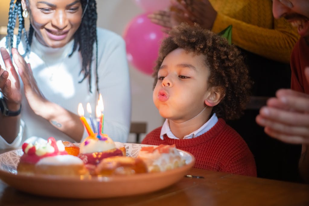 A joyful birthday celebration with a child blowing out candles surrounded by family, capturing a happy moment.